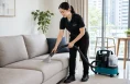 KleanSG cleaner vacuuming a fabric sofa during home cleaning in Singapore